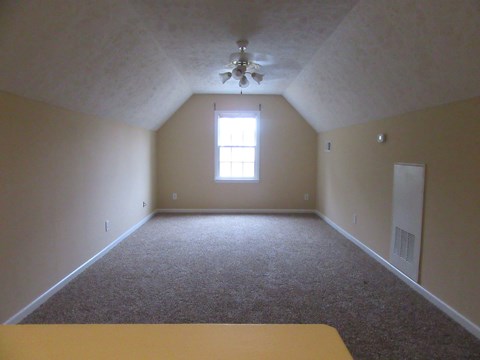 A room with a carpet floor and a ceiling fan.