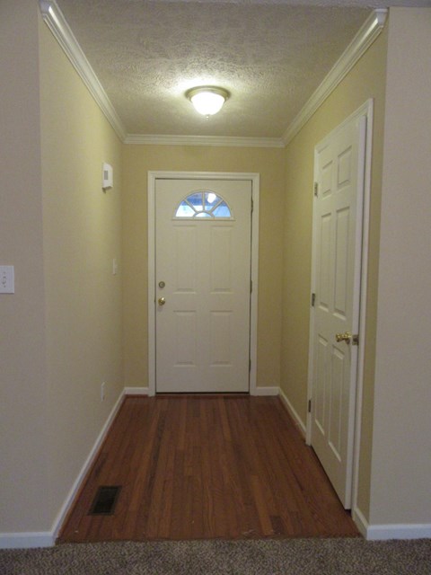 A hallway with a white door and a window above it.