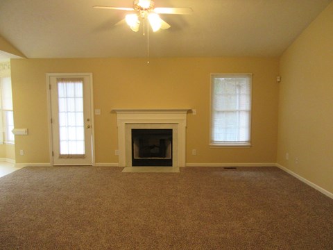 A living room with a fireplace and a ceiling fan.