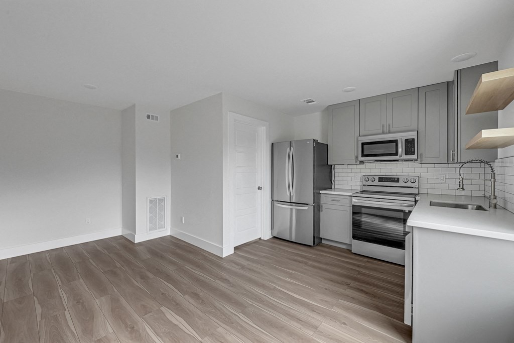 an empty kitchen with white cabinets and stainless steel appliances