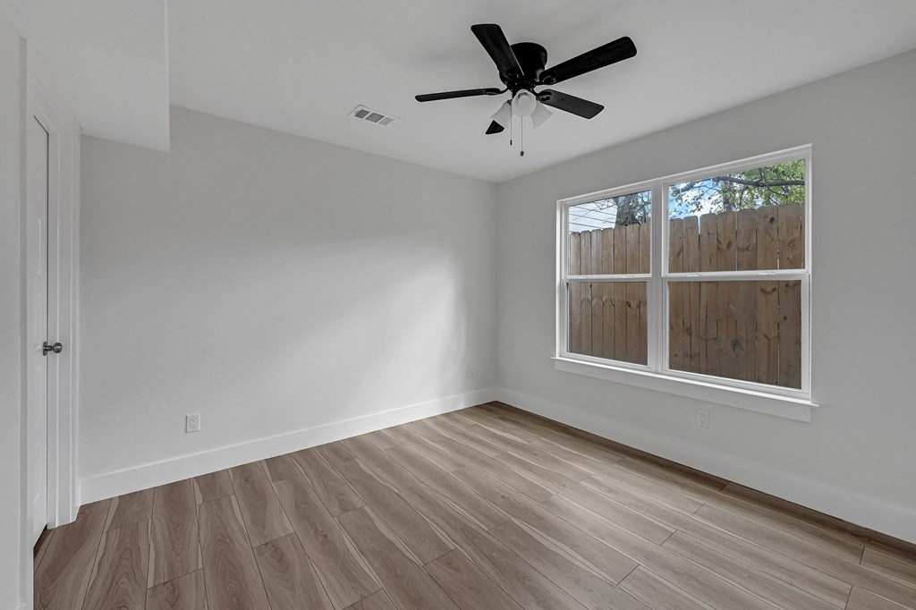 an empty bedroom with a window and a ceiling fan