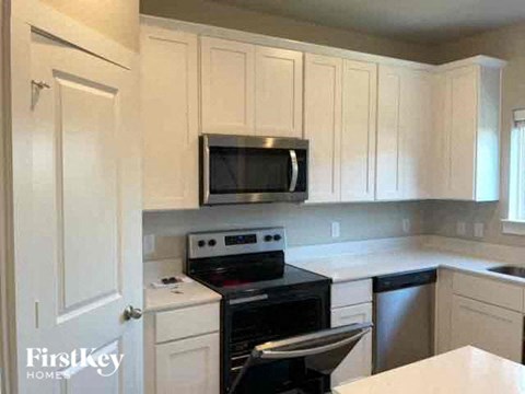 a kitchen with a stove and a microwave and white cabinets