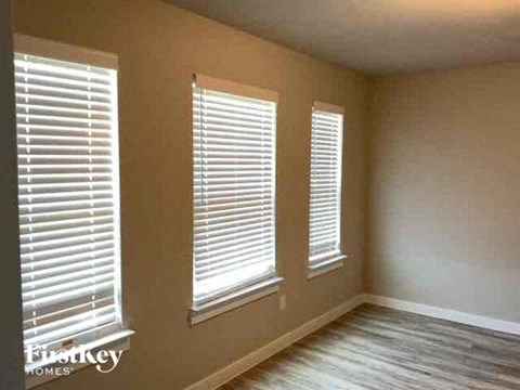 a living room with three windows with white blinds