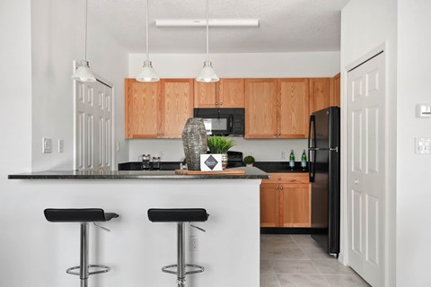 A kitchen with a black fridge and wooden cabinets.
