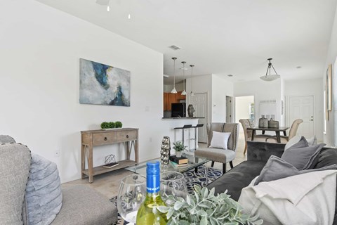 A living room with a grey couch, a wooden table, and a painting on the wall.