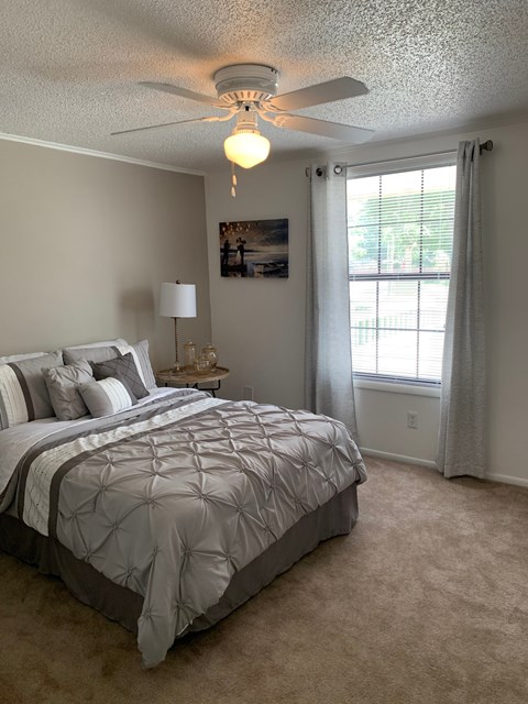 A bedroom with a large bed and a ceiling fan.