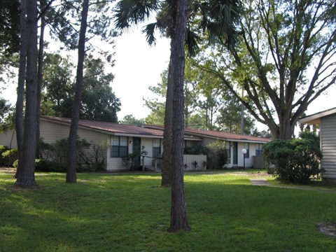 A house with a green lawn and trees in front.