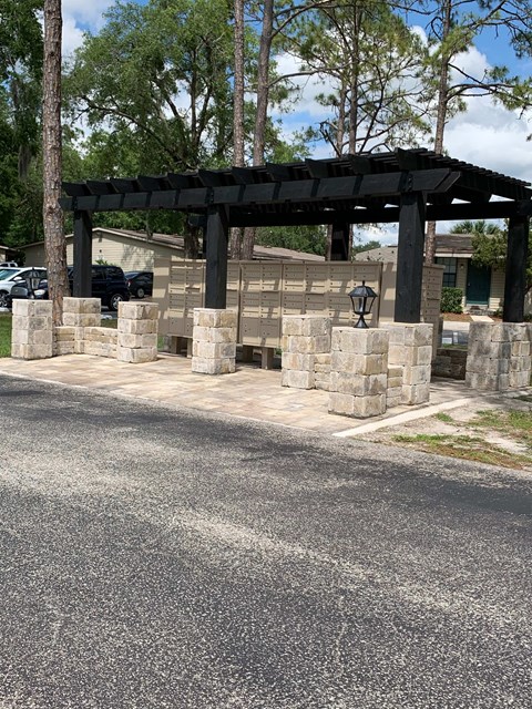 A black pergola is situated on a stone pillar.