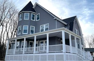a house with a wrap around porch and a steep roof