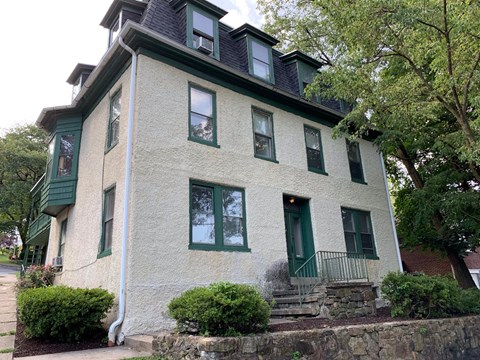a house with green windows and a stone wall