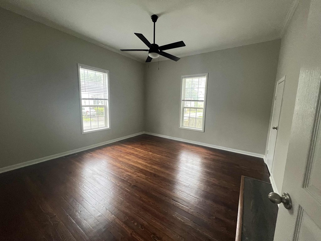 an empty living room with wood floors and a ceiling fan