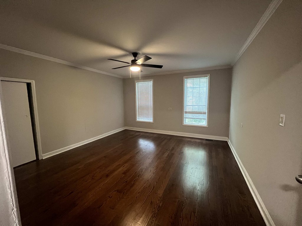 an empty living room with wood floors and a ceiling fan