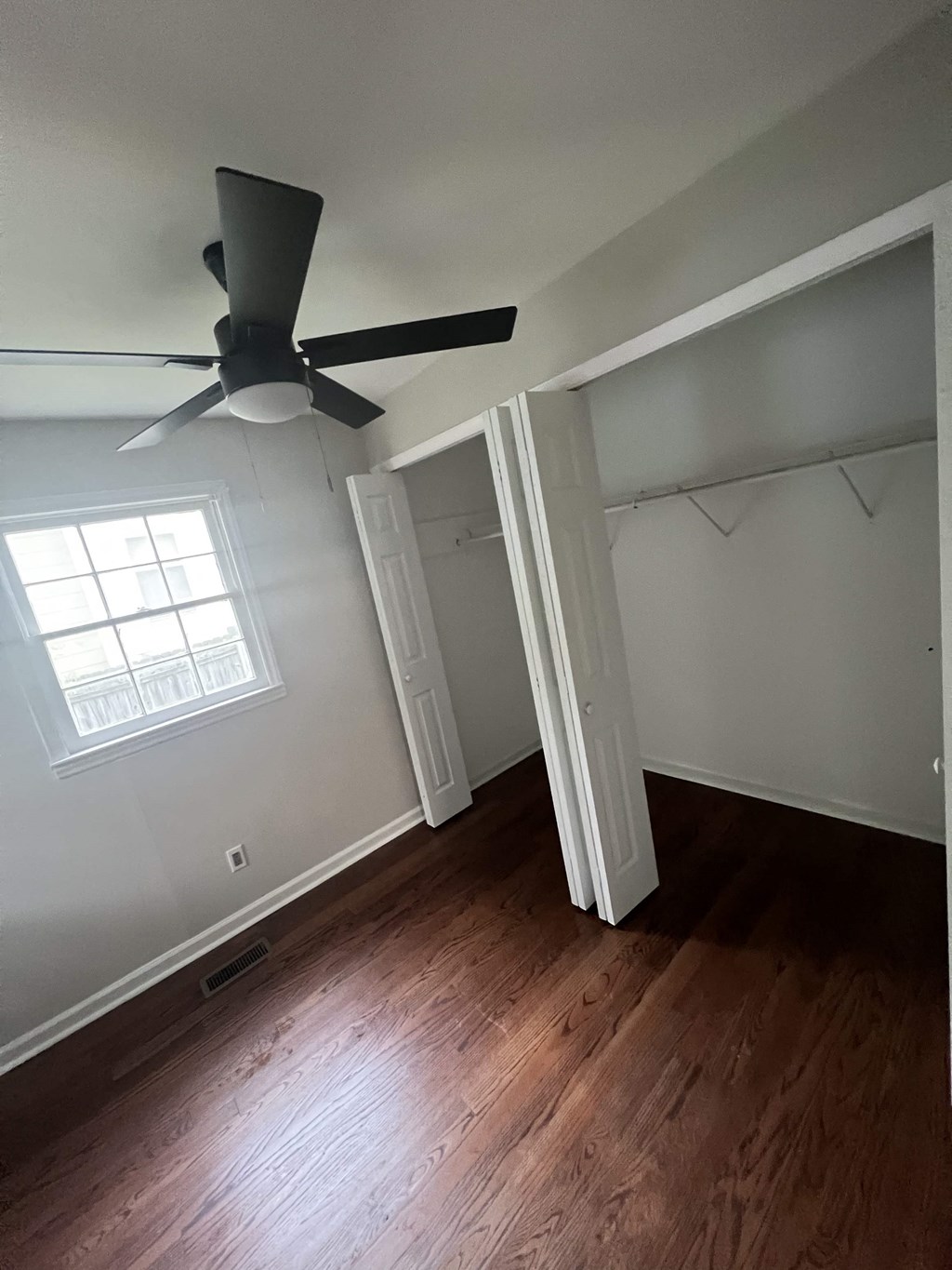 an empty bedroom with a ceiling fan and a closet