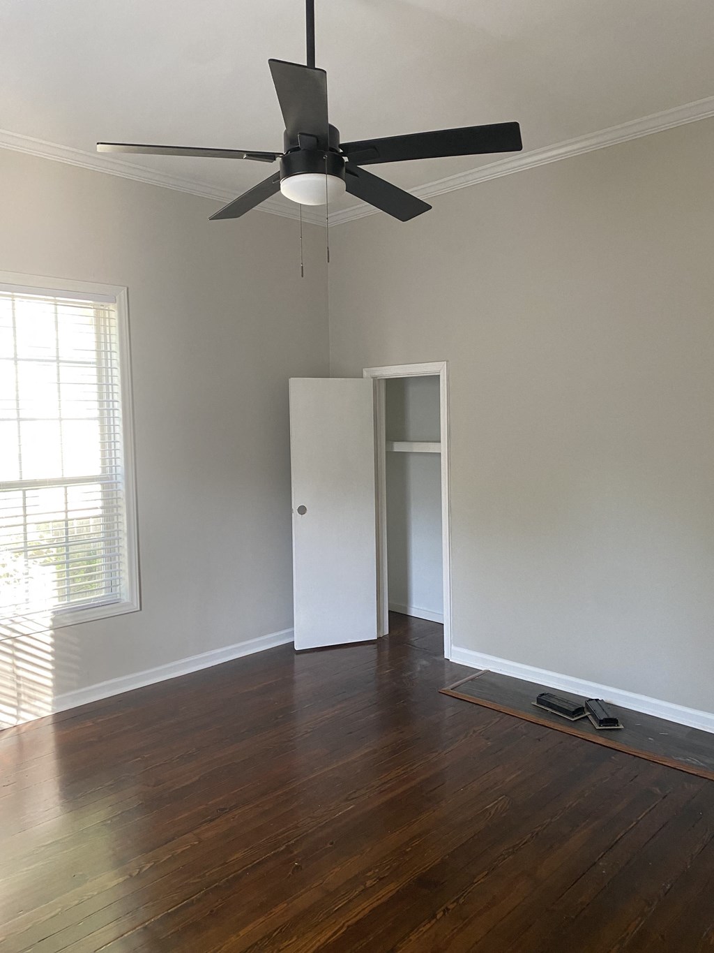an empty living room with wood floors and a ceiling fan