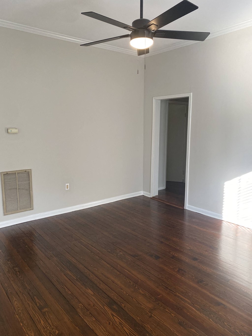 an empty living room with wooden floors and a ceiling fan