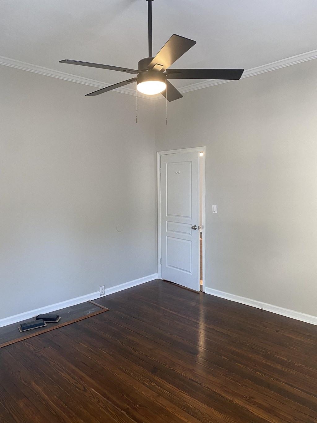 an empty living room with wood floors and a ceiling fan