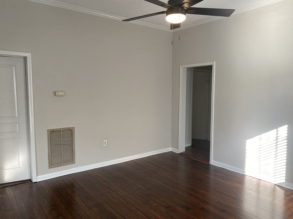 an empty living room with wood floors and a ceiling fan