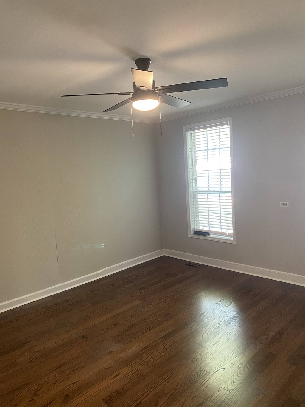 an empty living room with a ceiling fan and a window