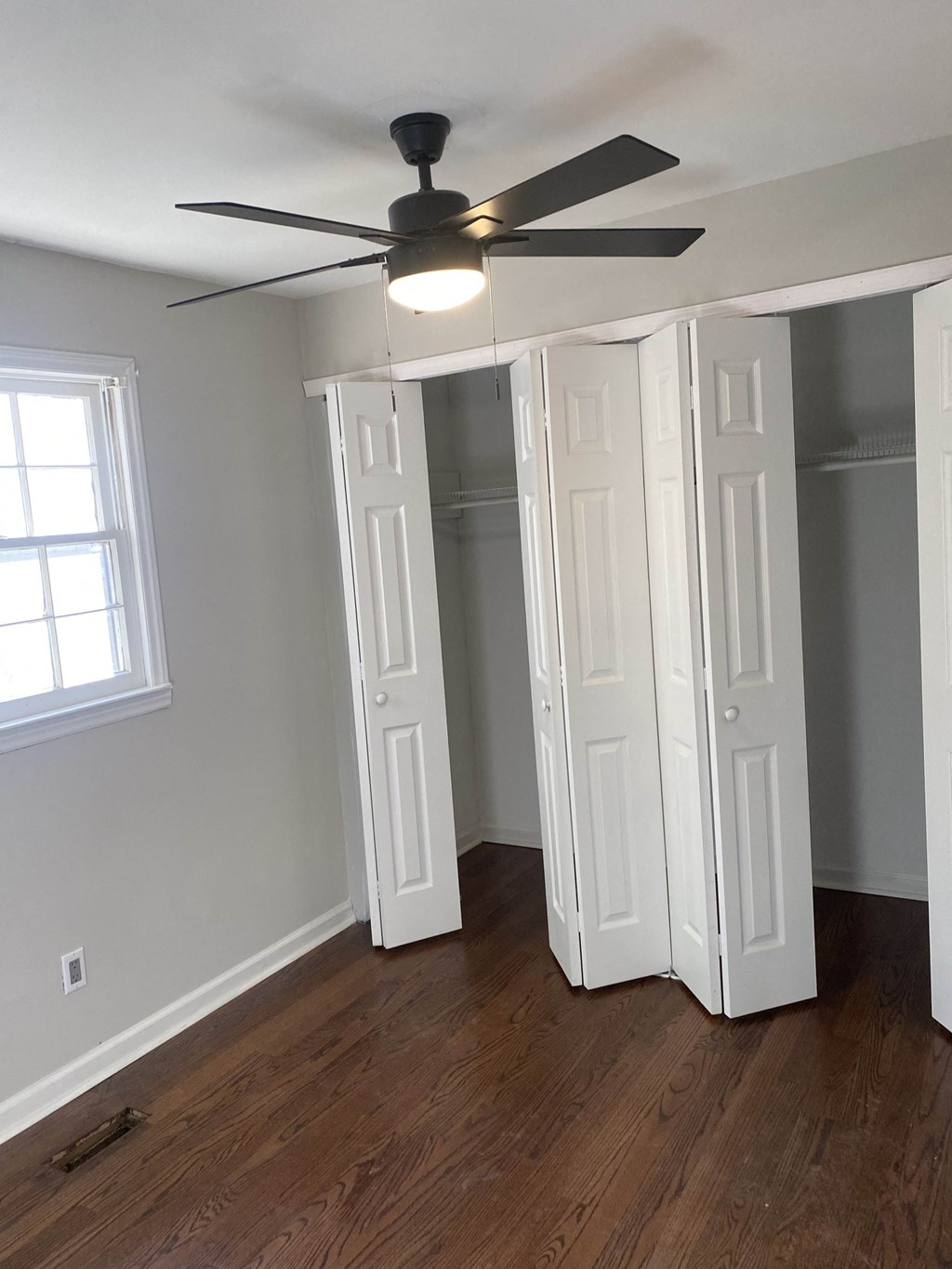 an empty bedroom with a ceiling fan and a closet