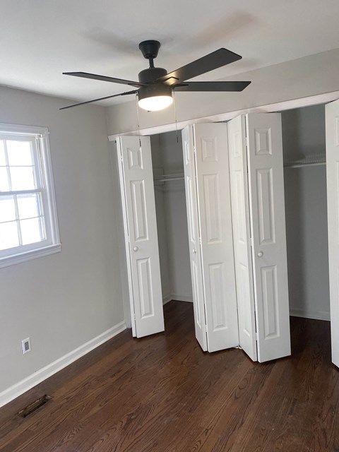 an empty bedroom with a ceiling fan and a closet