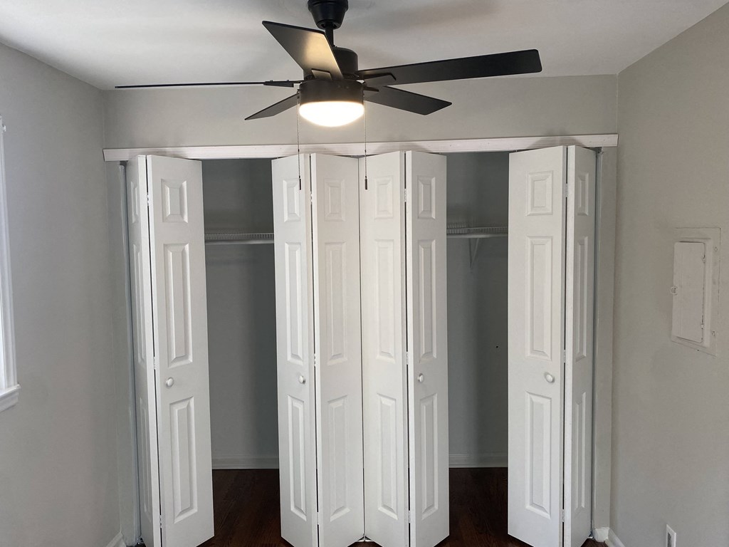 a room with four closet doors and a ceiling fan