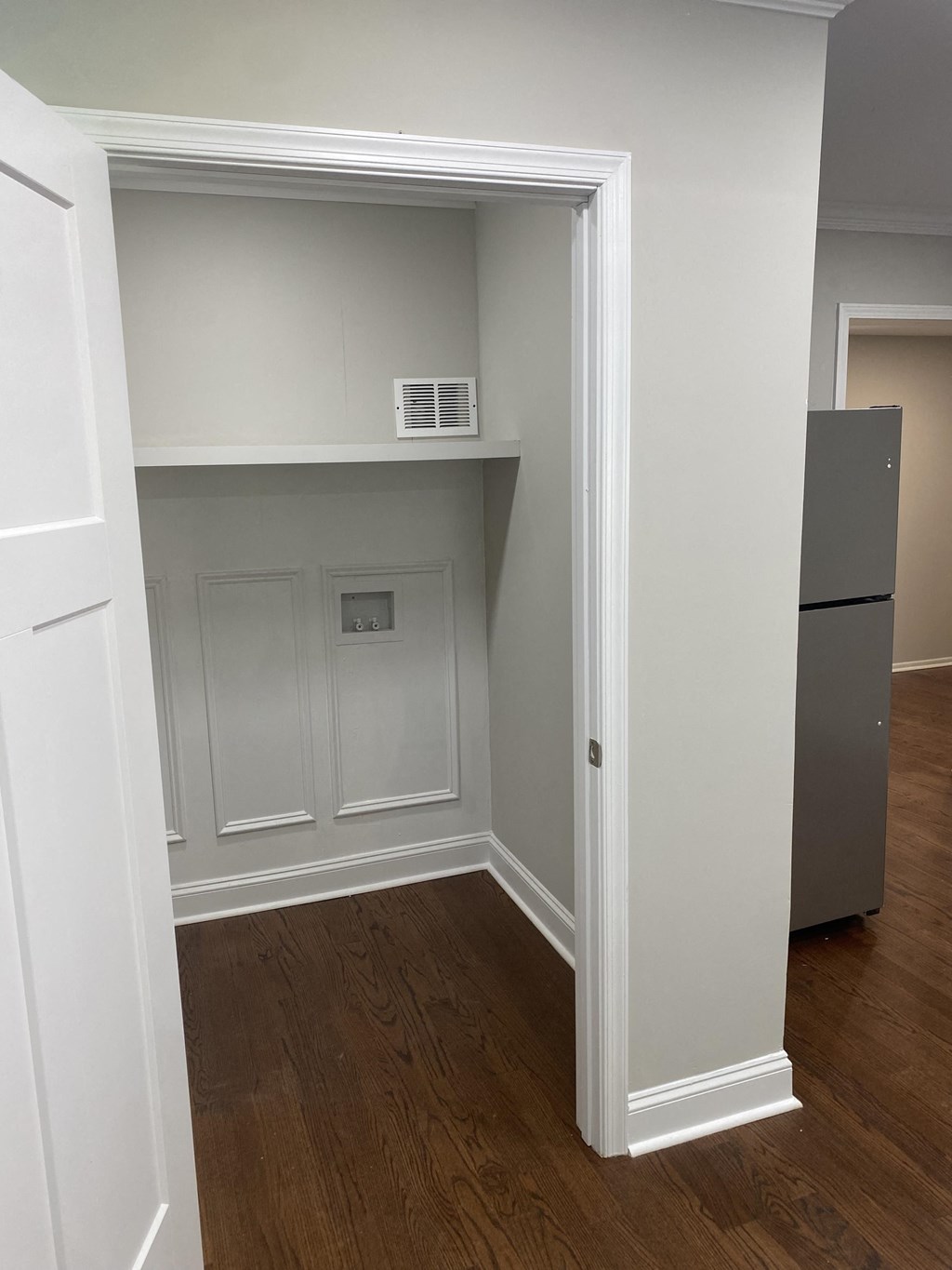 a hallway with a door open to a closet and a refrigerator