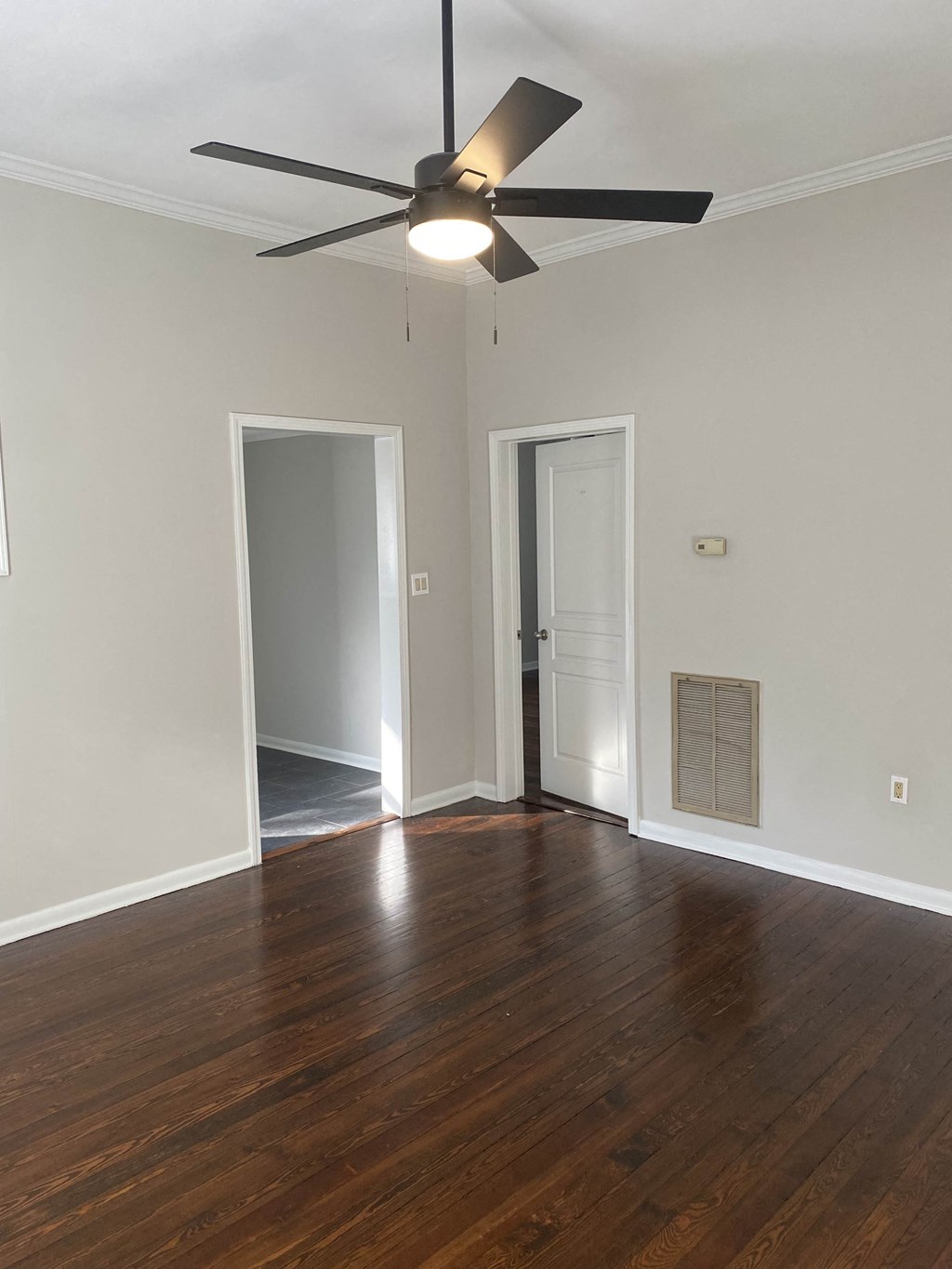 an empty living room with wood floors and a ceiling fan