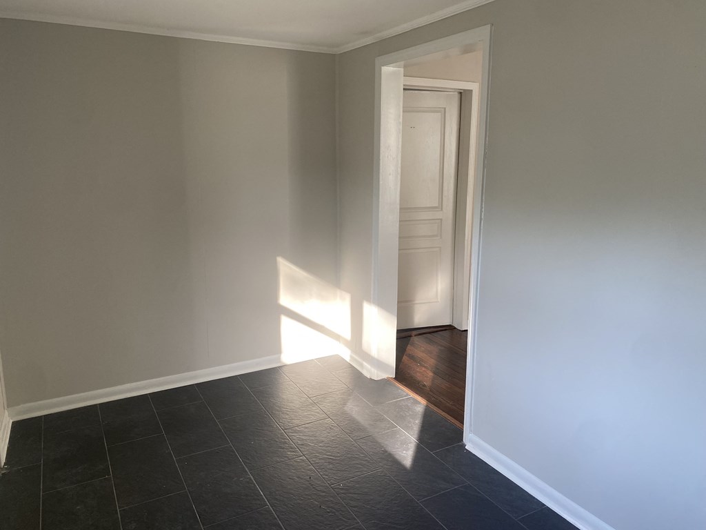 a room with white walls and black tile and a door