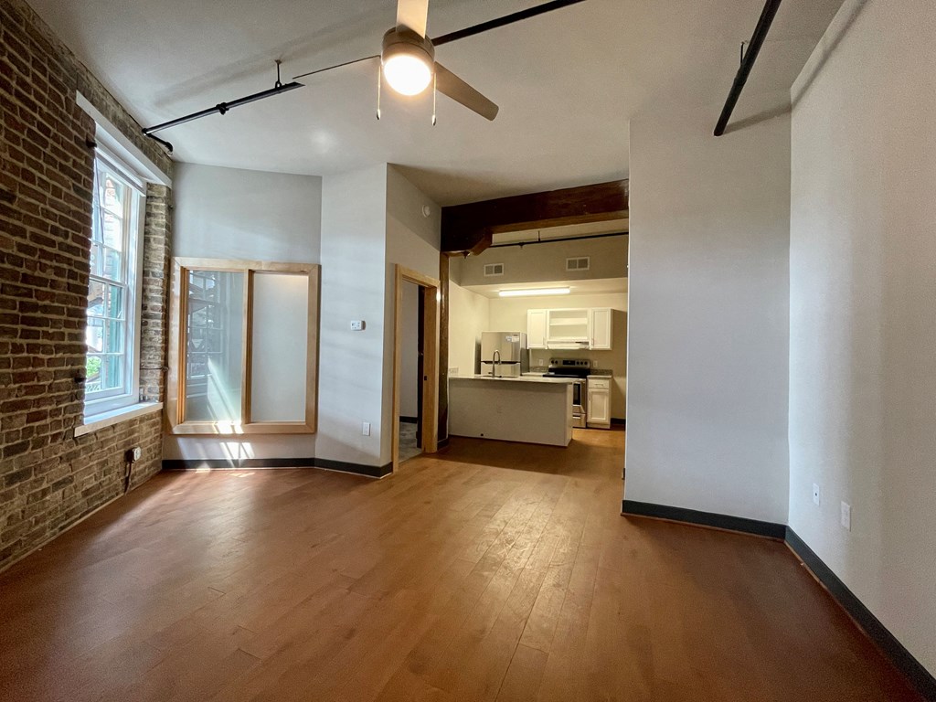 an empty living room with wood floors and a ceiling fan