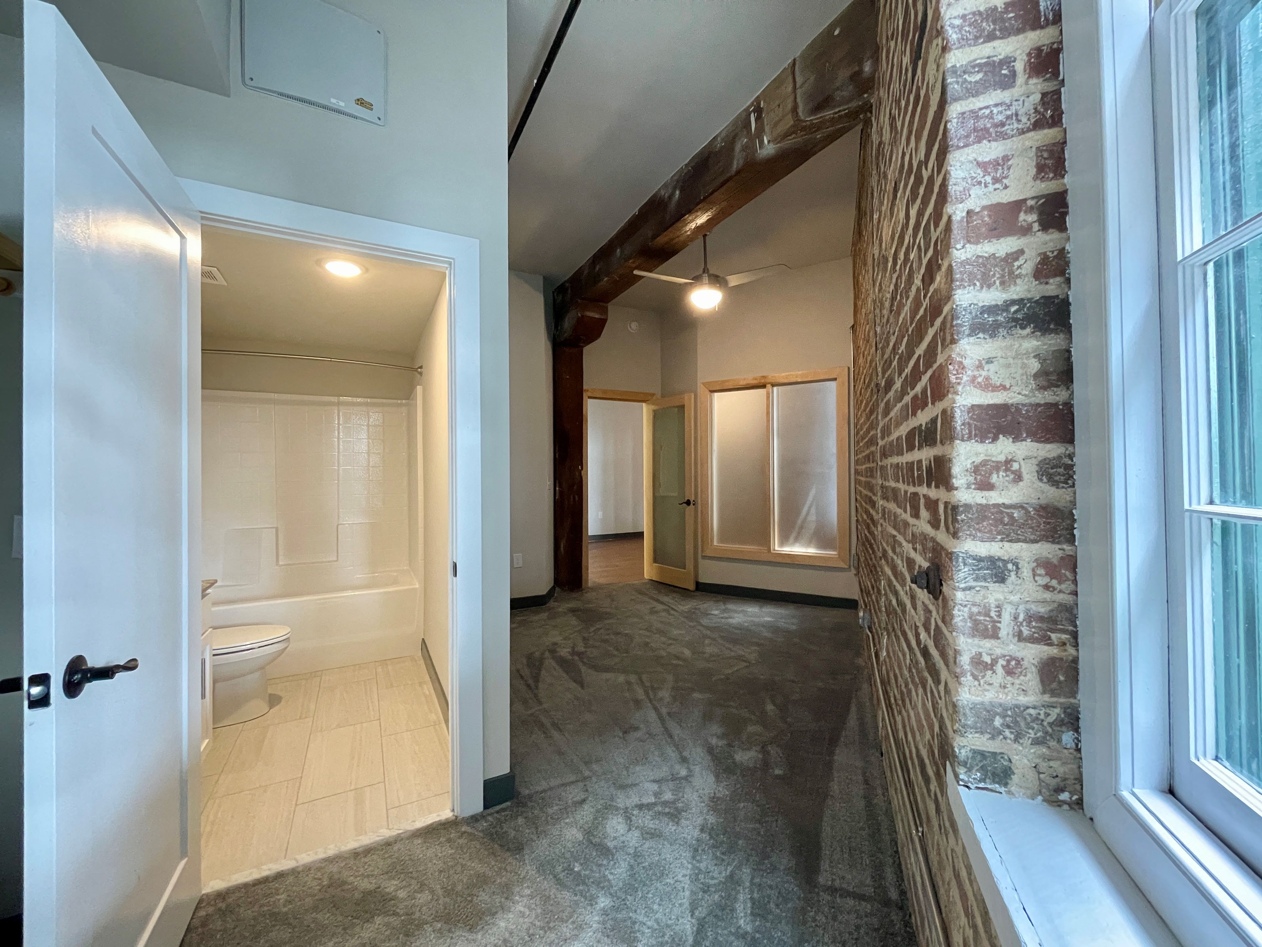 a renovated bathroom and living room with a brick wall