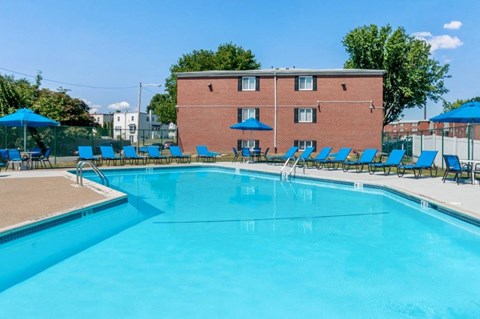 a swimming pool with chairs and umbrellas in front of a building