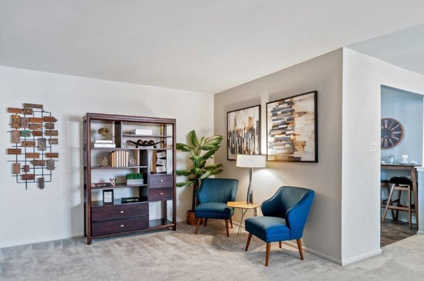 a living room with two blue chairs and a cabinet