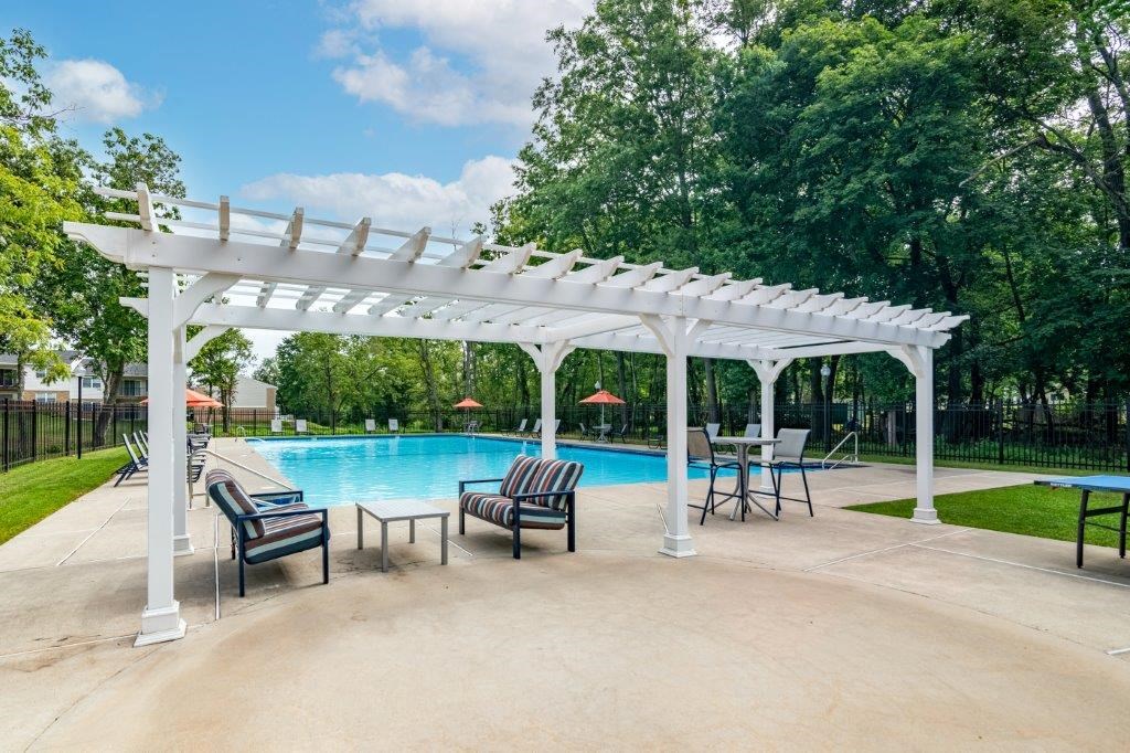 a swimming pool with a pergola and chairs around it