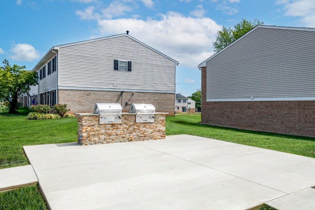 a concrete driveway in front of a house with two barbecue pits
