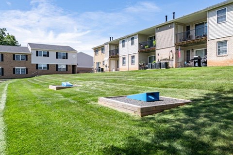 a fire pit in the grass in front of an apartment building
