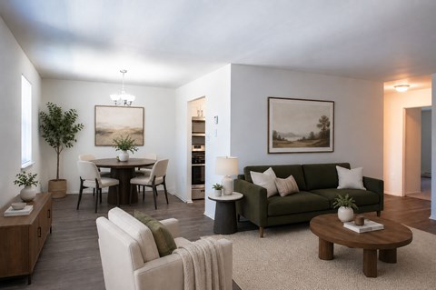 A living room with a green couch, a coffee table, and a dining table with chairs.