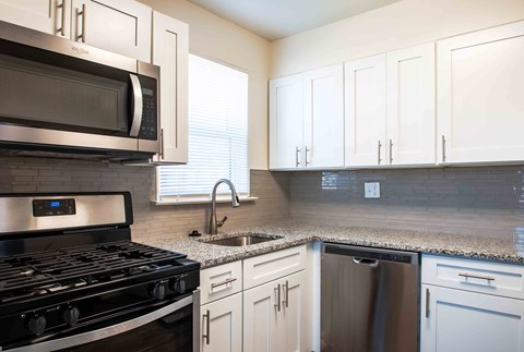 A kitchen with a black stove top oven and white cabinets.