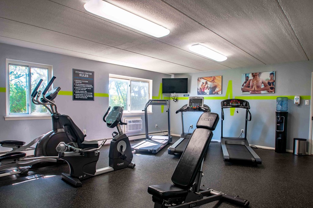 a gym with various machines and weights in a room with windows