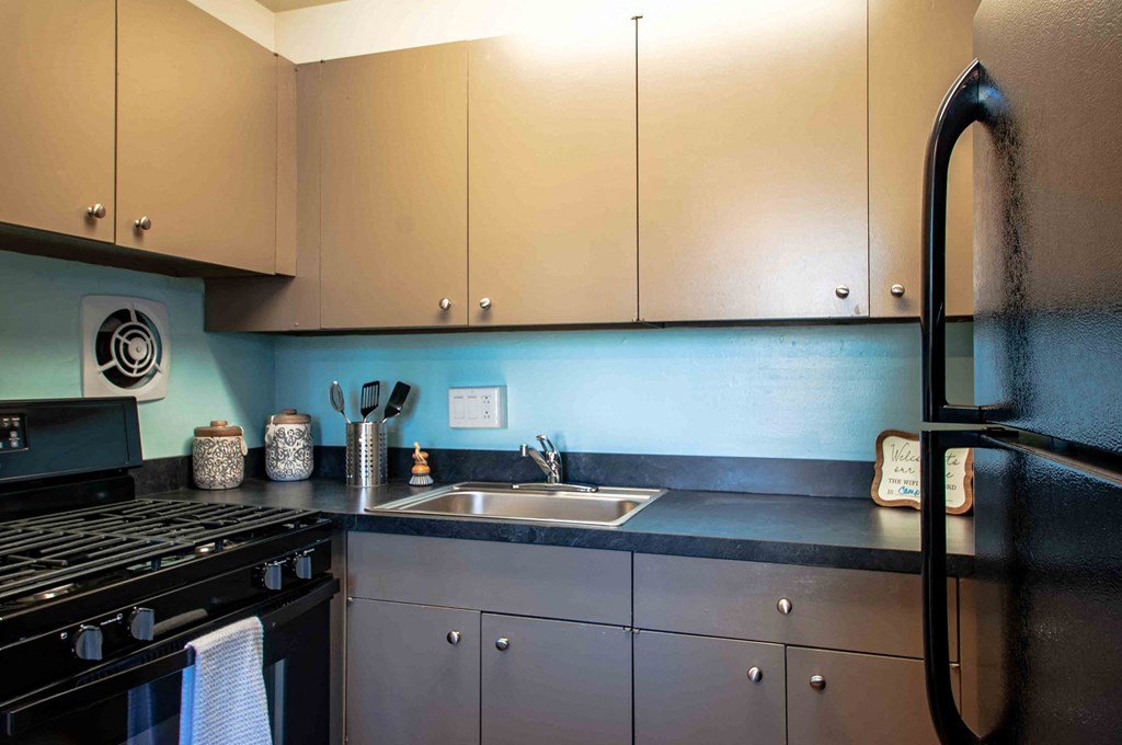 a kitchen with white cabinets and a sink and a stove