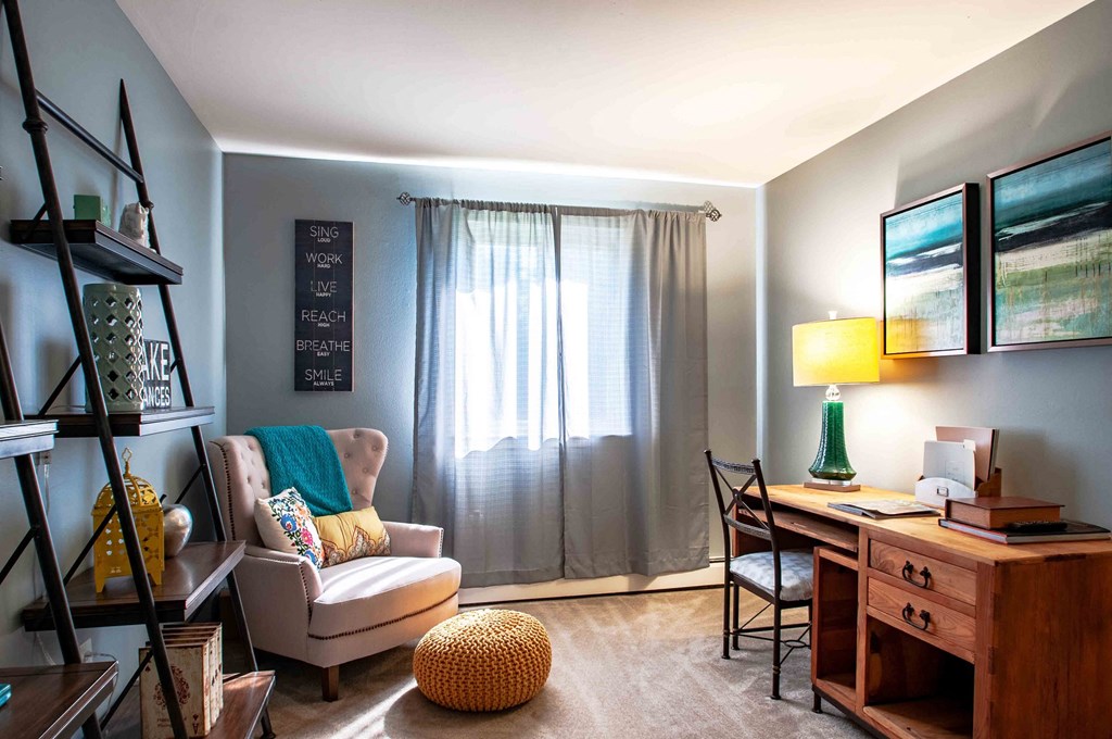 a living room with a couch and a chair and a desk