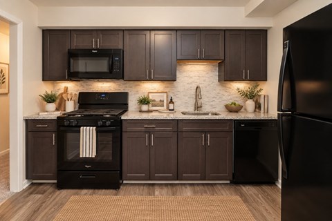 A modern kitchen with dark brown cabinets and black appliances.
