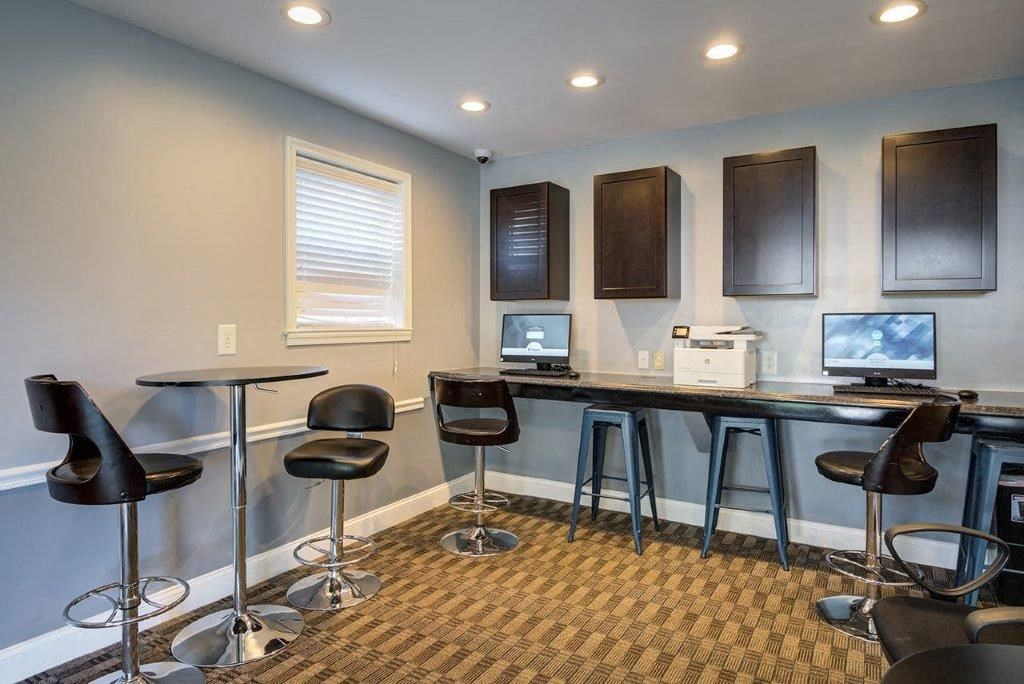 a room with a bar with chairs and computers