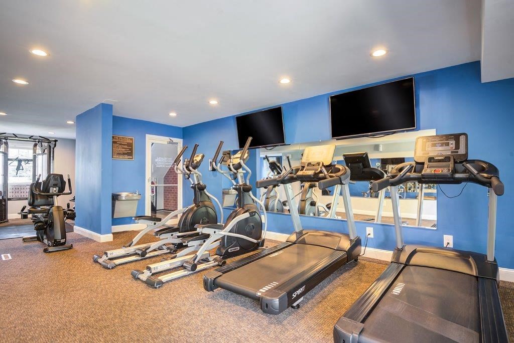 a gym with cardio machines and televisions