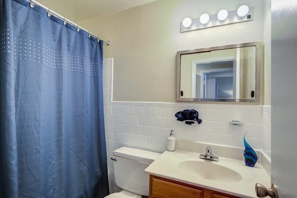 a bathroom with a blue shower curtain and a toilet and sink