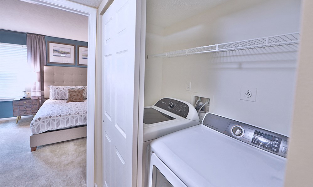a laundry room with a bed and a washer and dryer