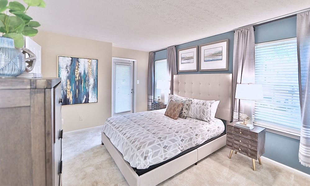 a bedroom with a bed and a dresser and windows