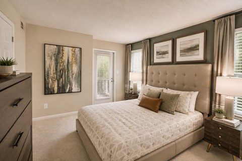 A bedroom with a large bed, a dresser, and a painting on the wall.