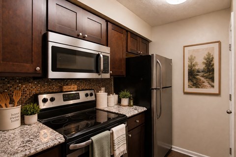 A kitchen with a stove top oven, microwave, and refrigerator.