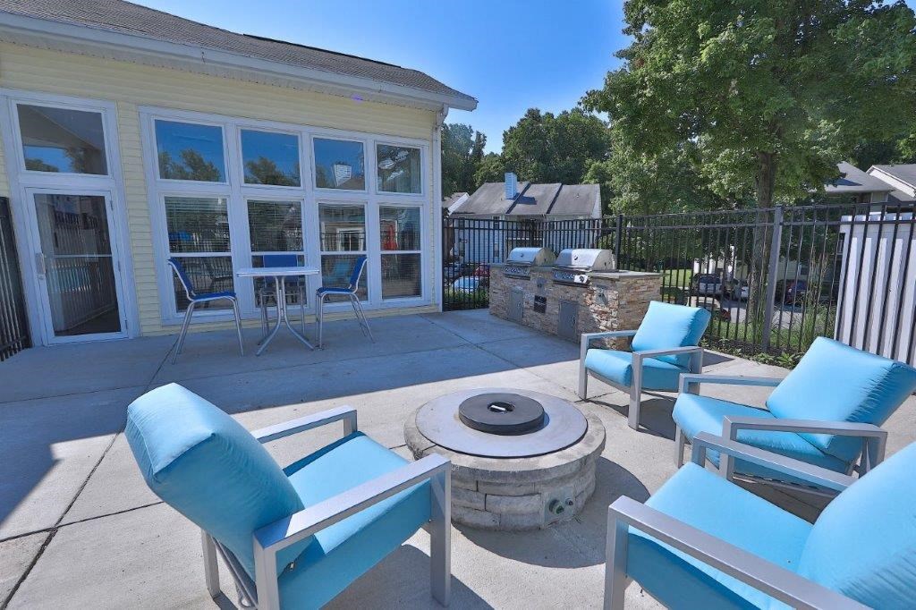 a patio with blue chairs and a fire pit
