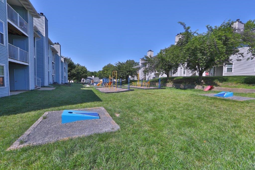 a grassy yard with a seesaw and balls in the grass